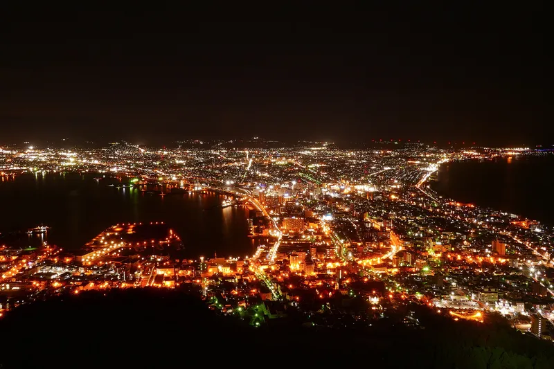 The night view of Hakodate from Mount Hakodate, city lights filling the strip of land between two dark bays