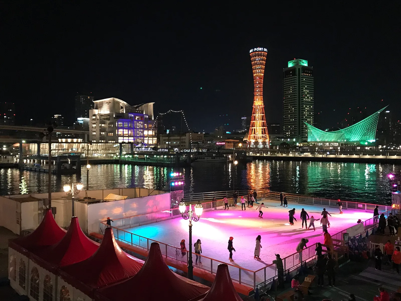 Kobe Port Tower and the illuminated harbor of Kobe at night, seen across the water