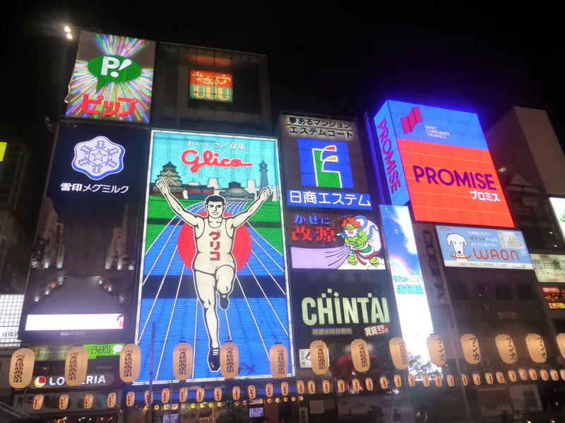 Dotonbori canal in Osaka at night, packed with neon signs and the Glico running man billboard