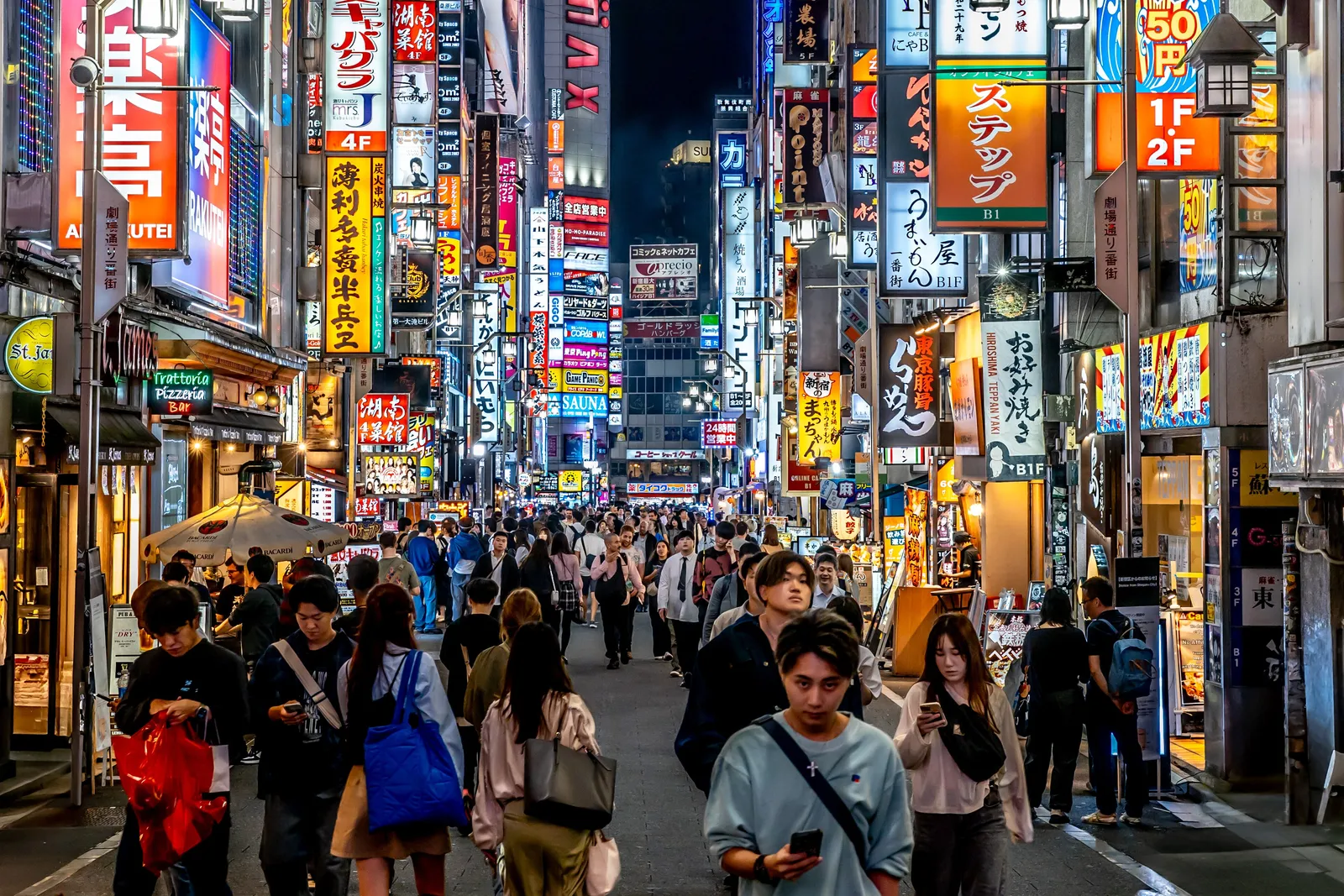Tokyo skyline and Shibuya crossing glowing with neon signs at dusk